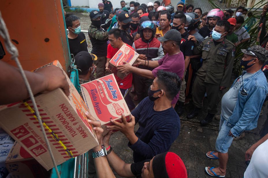 People queue up for food aid in Mamuju.