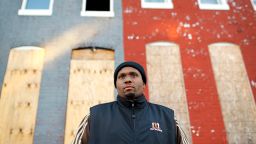 In this Dec. 29, 2015 photo, Dante Barksdale, an outreach coordinator for Baltimore's Safe Streets program, stands outside blighted row houses in Baltimore. "Every corner has one: A guy in a wheelchair, or several guys on the corner with a slit up the middle of their stomach where their internal organs were hit with bullets," Barksdale said. "For some it's a medal of honor. They'll say, 'I've got battle scars.' They'll say, 'I've been through a war.' But those scars demoralize a community. You have kids seeing those scars in a positive light. There is always someone who will buy in. It perpetuates the violence, make no mistake."