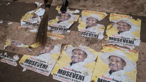 A worker sweeps the ground covered with campaign posters of President Yoweri Museveni on January 17, 2021 on a street in Kampala, Uganda.