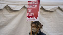 A demonstrator holds a sign reading "Tax Bezos" during a protest outside Amazon.com Inc. headquarters in Seattle, Washington, U.S., on Friday, Nov. 27, 2020. Amazon.com Inc. will pay the employees who pack and deliver its goods a one-time bonus of up to $300, extra compensation that comes as the company faces a union drive and criticism from others for rolling back pandemic hazard pay. 