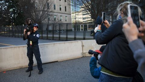 People take photos of a police dog posing with an officer outside the Capitol.
