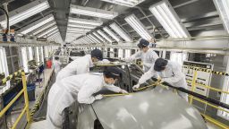 Employees wearing protective masks place yellow tape on a crossover sport utility vehicle (SUV) in the paint shop at the Geely Automobile Holdings Ltd. plant in Ningbo, Zhejiang Province, China, on Tuesday, April 28, 2020.