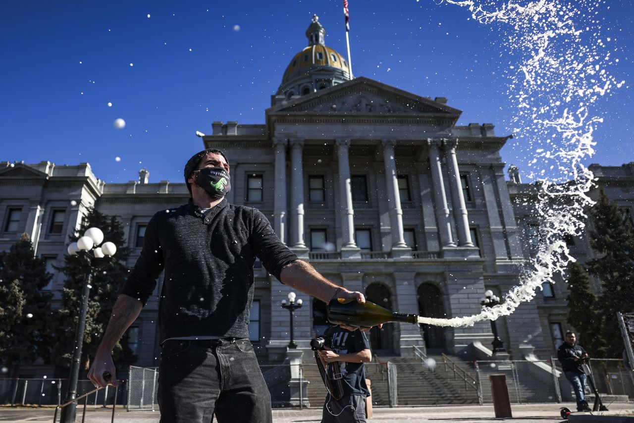 Keith Hodson pops a bottle of champagne on the steps of the Colorado State Capitol in Denver.