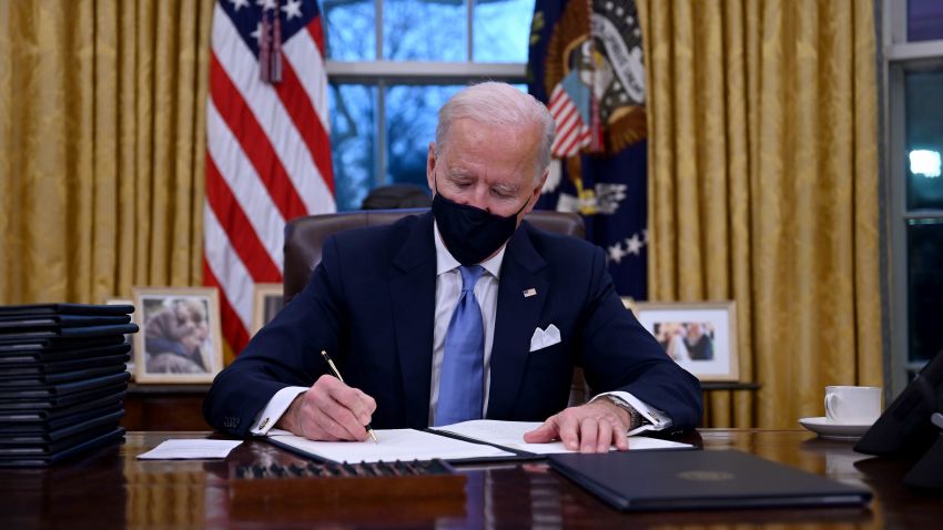 TOPSHOT - US President Joe Biden sits in the Oval Office as he signs a series of orders at the White House in Washington, DC, after being sworn in at the US Capitol on January 20, 2021. - US President Joe Biden signed a raft of executive orders to launch his administration, including a decision to rejoin the Paris climate accord. The orders were aimed at reversing decisions by his predecessor, reversing the process of leaving the World Health Organization, ending the ban on entries from mostly Muslim-majority countries, bolstering environmental protections and strengthening the fight against Covid-19. (Photo by Jim WATSON / AFP) (Photo by JIM WATSON/AFP via Getty Images)