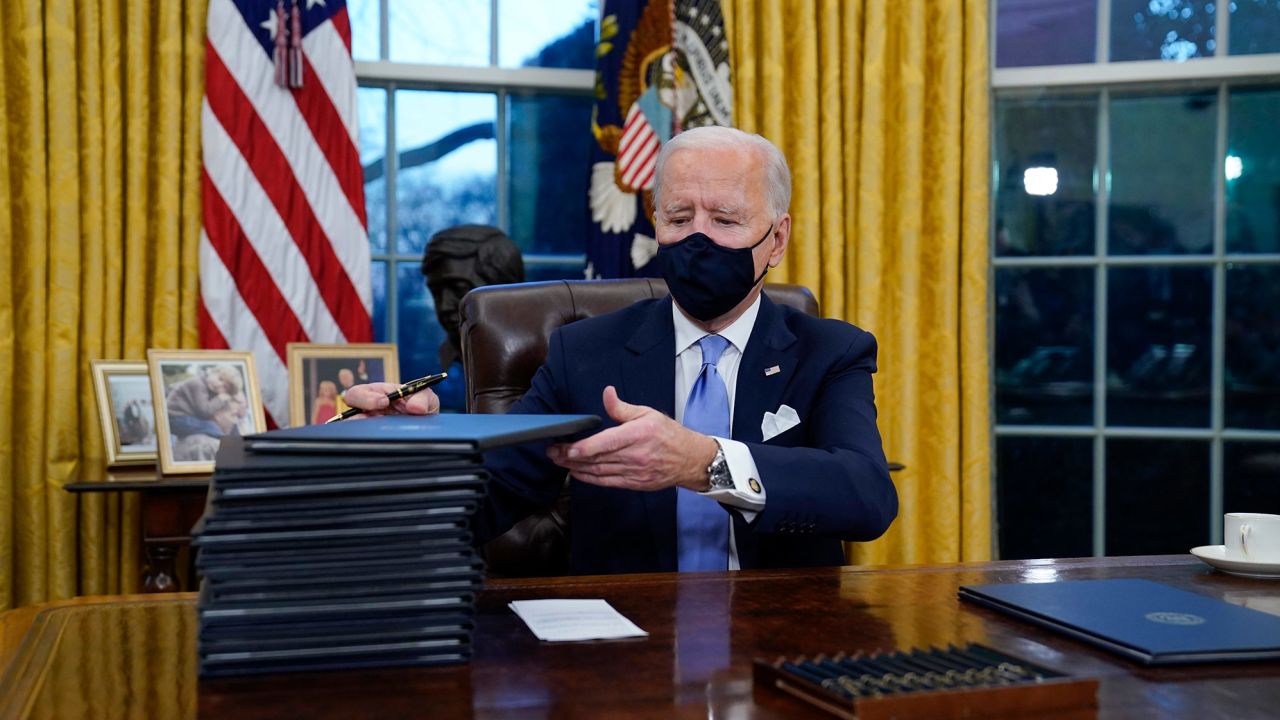 President Joe Biden signs his first executive orders in the Oval Office of the White House on Wednesday, Jan. 20, 2021, in Washington. 