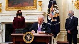 President Joe Biden signs executive orders after speaking about the coronavirus, accompanied by Vice President Kamala Harris, left, and Dr. Anthony Fauci, director of the National Institute of Allergy and Infectious Diseases, right, in the State Dinning Room of the White House, Thursday, Jan. 21, 2021, in Washington. (AP Photo/Alex Brandon)