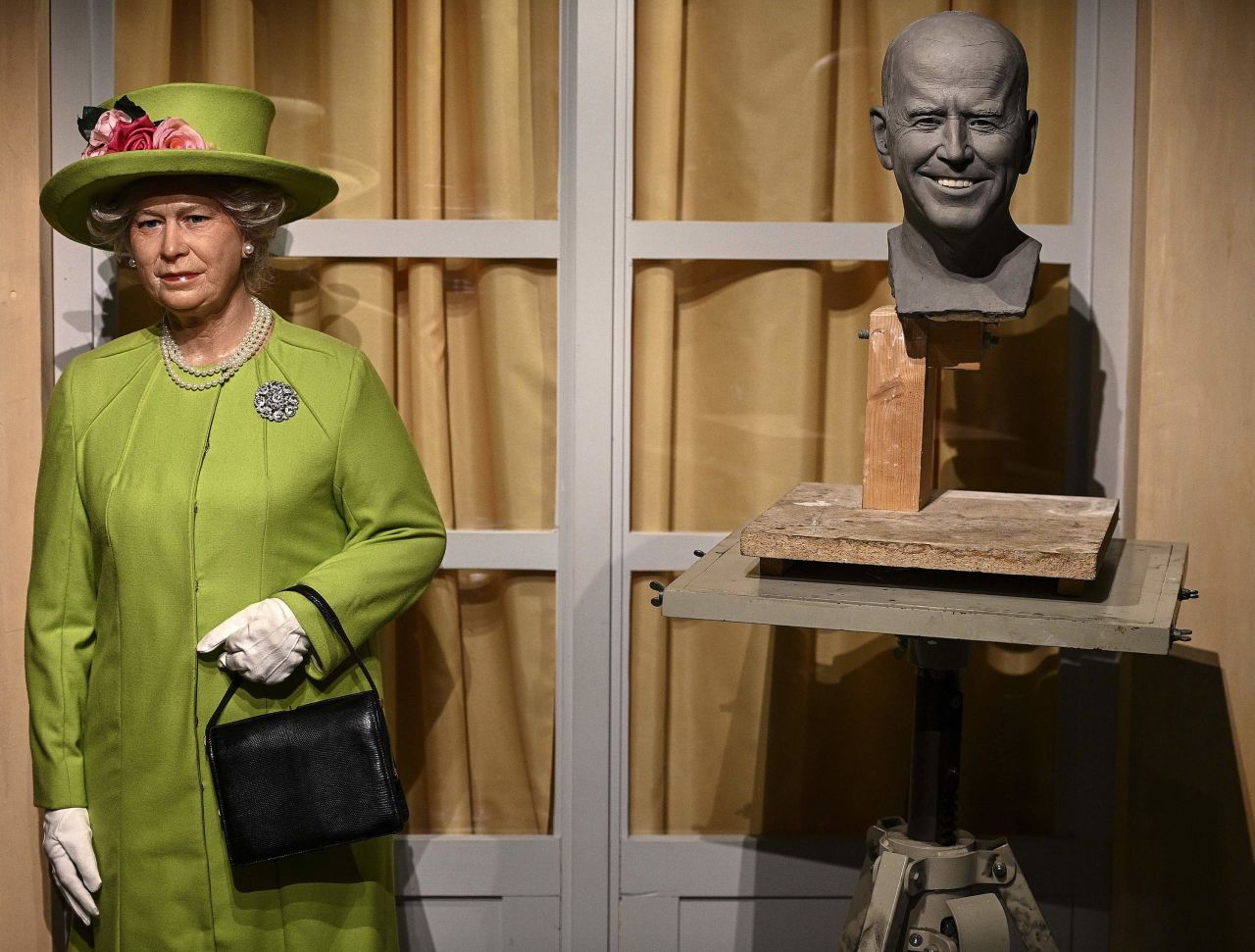 An unfinished wax head of US President Joe Biden is seen next to a statue of Britain's Queen Elizabeth II at the Grevin Museum in Paris on Tuesday, January 19.