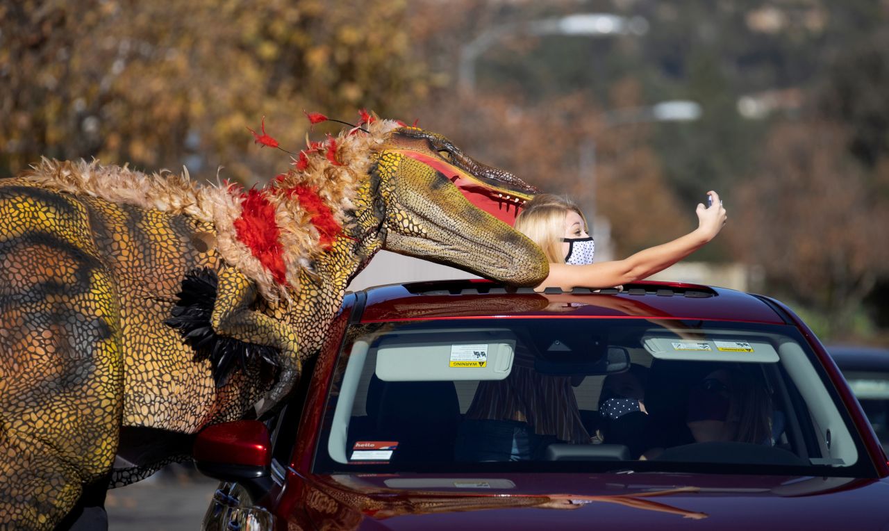 Samantha Bailey takes a selfie with a staff member dressed like a raptor at the Jurassic Quest dinosaur park in Pasadena, California, on Friday, January 15.