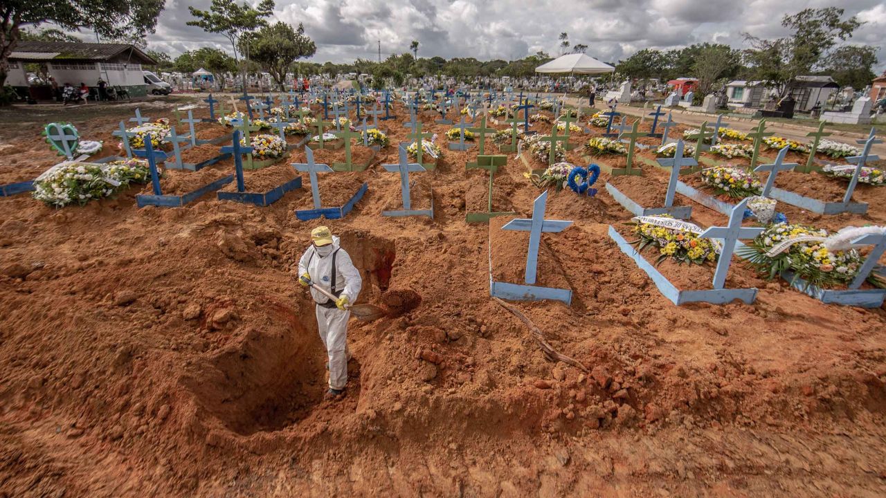 Worker wearing personal protective equipment (PPE) digs a grave at a cemetery in Manaus, Brazil, on Tuesday, Jan. 19, 2021. Severe oxygen shortages at hospitals in Brazil's Amazon prompted local authorities to impose a curfew and airlift patients to other states to deal with the onslaught of a second coronavirus wave. Photographer: Jonne Roriz/Bloomberg via Getty Images