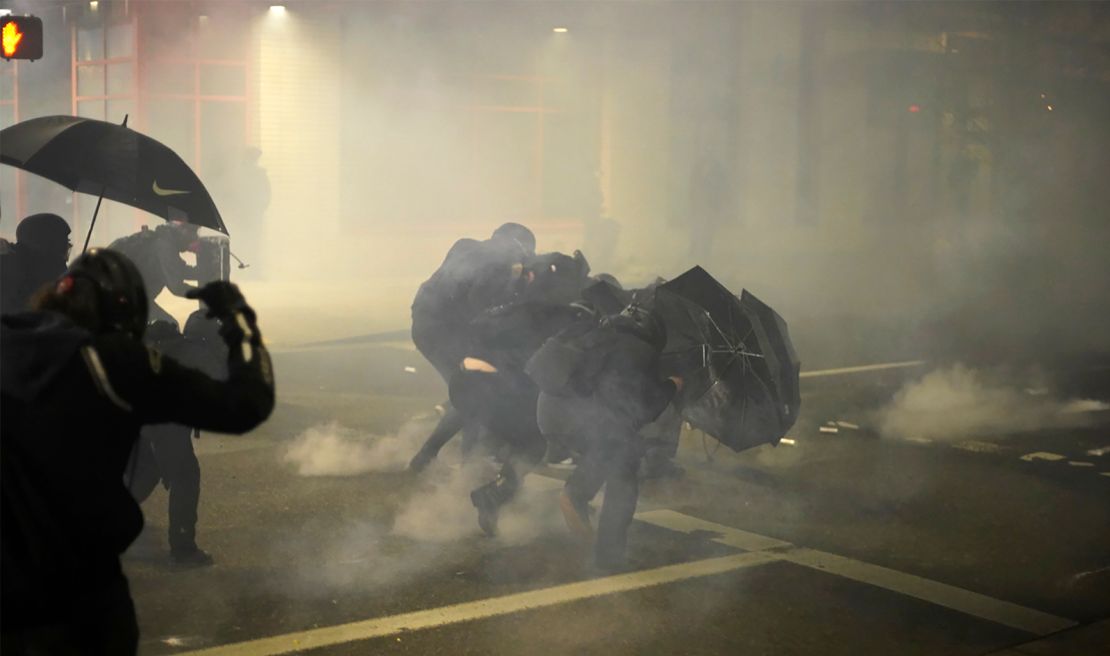 Protesters shield themselves from chemical irritants Wednesday evening outside the US Immigrations and Customs Enforcement building in Portland, Oregon.