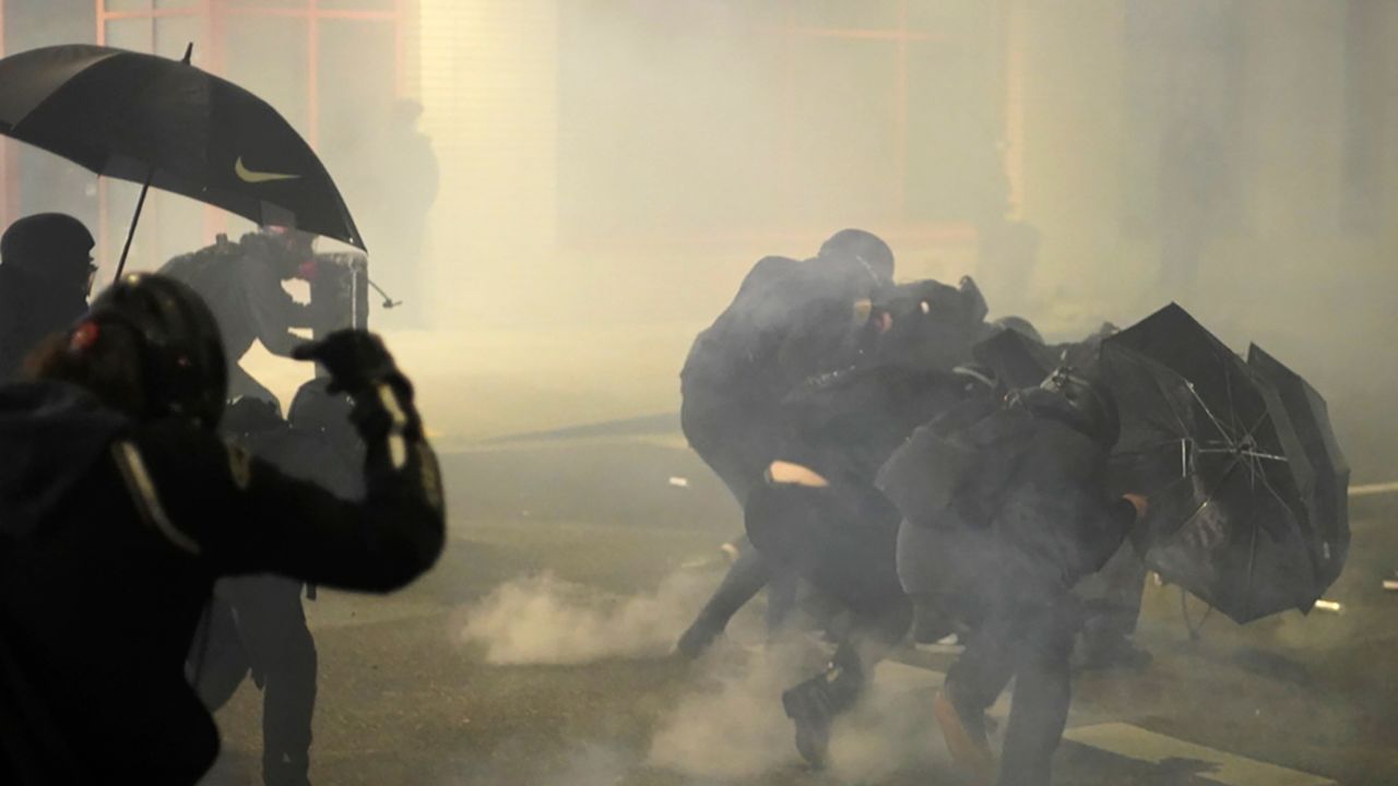 A group of protesters shield themselves from chemical irritants as they demonstrate Wednesday evening, Jan. 20, 2021, outside the U.S. Immigrations and Customs Enforcement (ICE) building in Portland, Ore. (Assfault Pirates via AP)