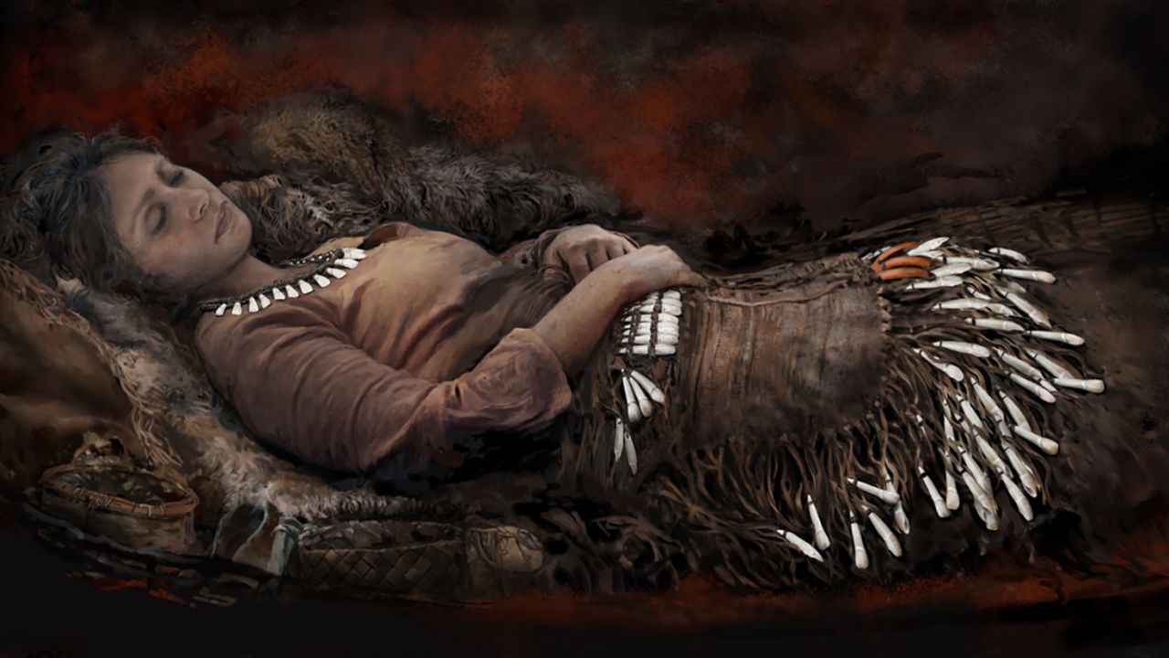 This illustration reconstructs one of the graves, which included 90 elk teeth placed next to the hips and thighs of the body, possibly attached to a garment like an apron. There were elk teeth pendants also on the waist. Red ochre was sprinkled on top of the deceased.