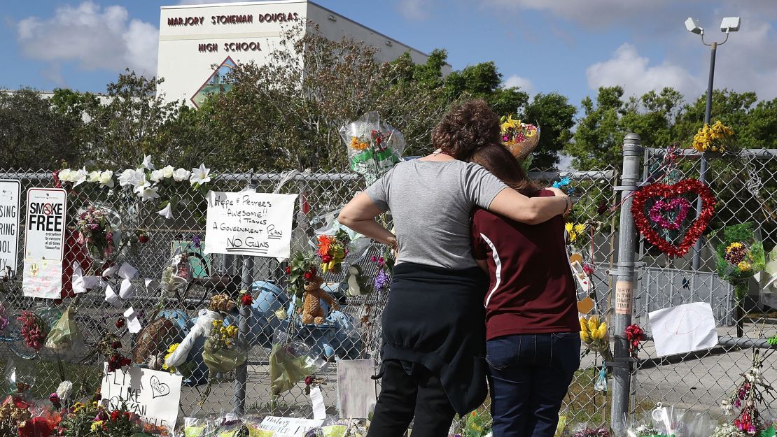 Margarita Lasalle, right, the budget keeper, and Joellen Berman, the guidance data specialist, look on at the memorial in front of Marjory Stoneman Douglas High School as teachers and staff are allowed to return to the school for the first time since the mass shooting on campus on February 23, 2018 in Parkland, Florida. 