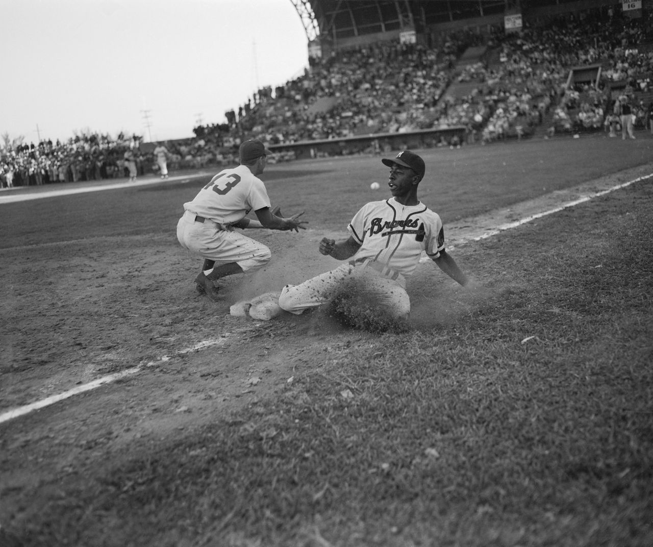 Aaron slides back to third base during an exhibition game in 1954. Aaron's career began in the Negro Leagues before he broke into the majors with the Milwaukee Braves.