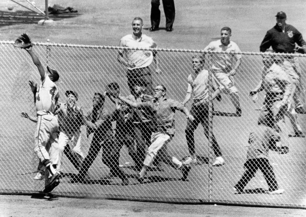 Fans rush to the fence at San Francisco's Candlestick Park as Aaron reaches for a catch in 1961. Aaron won three Golden Glove awards for his fielding during his career.