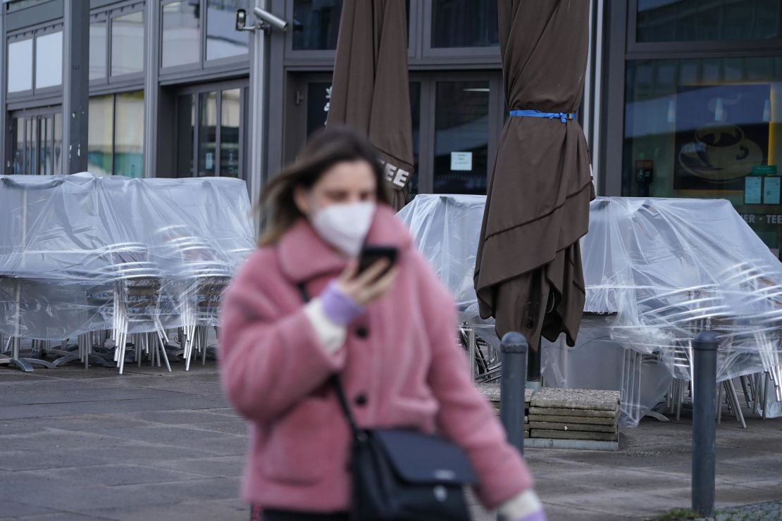 A woman wearing an FFP2 face mask walks past a shuttered cafe in Berlin, Germany.
