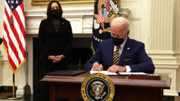 U.S. President Joe Biden signs an executive order as Vice President Kamala Harris looks on during an event on economic crisis in the State Dining Room of the White House January 22, 2021 in Washington, DC. 