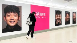 People walk by Chinese short video app Kuaishou advertisement painted with smiling faces of its users at a subway station on January 10, 2021 in Beijing, China. 