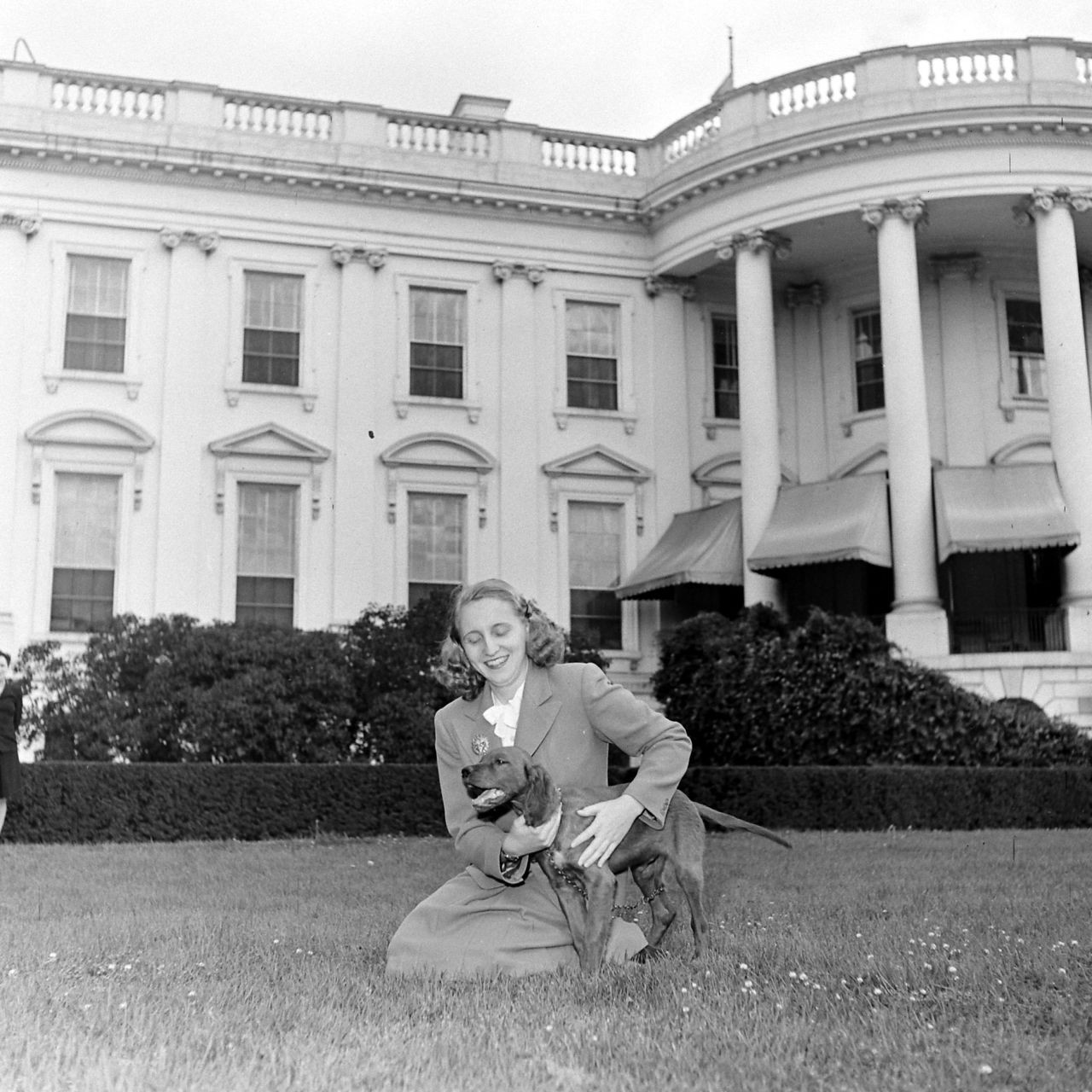 Harry Truman's daughter, Margaret, holds their Irish setter, Mike, outside the White House in 1945.
