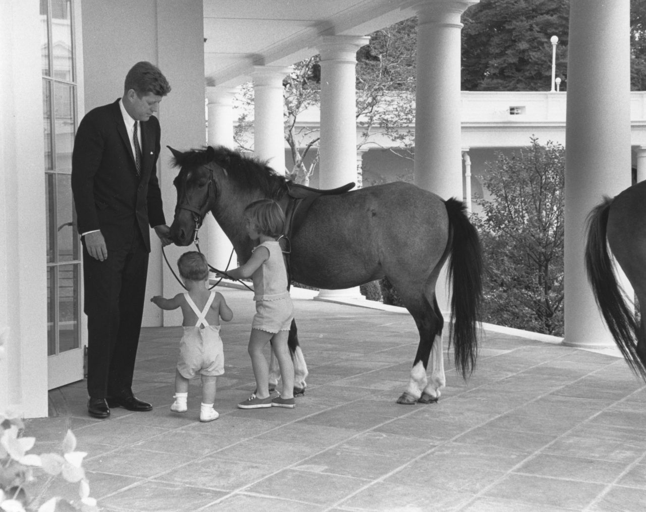 John F. Kennedy and his children John and Caroline play with their pony Macaroni in 1962.
