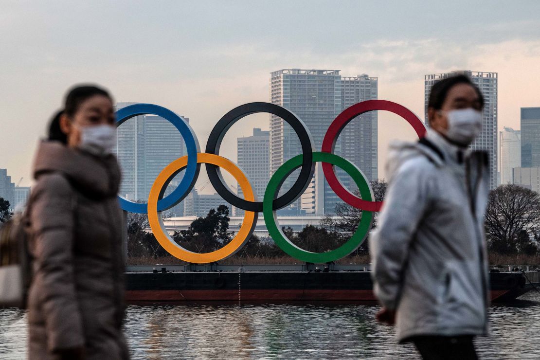 People wearing face masks walk past the Olympic Rings on January 22, 2021 in Tokyo, Japan.