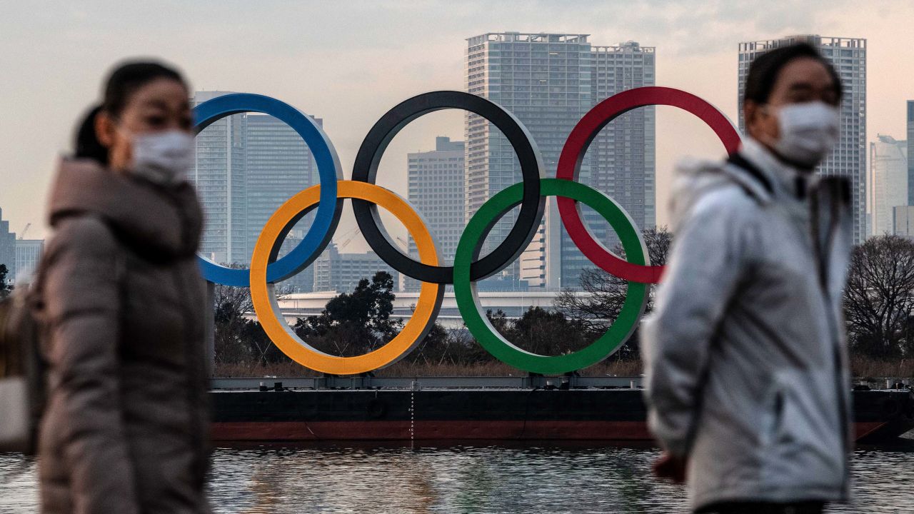 People wearing face masks walk past the Olympic Rings on January 22, 2021 in Tokyo, Japan.