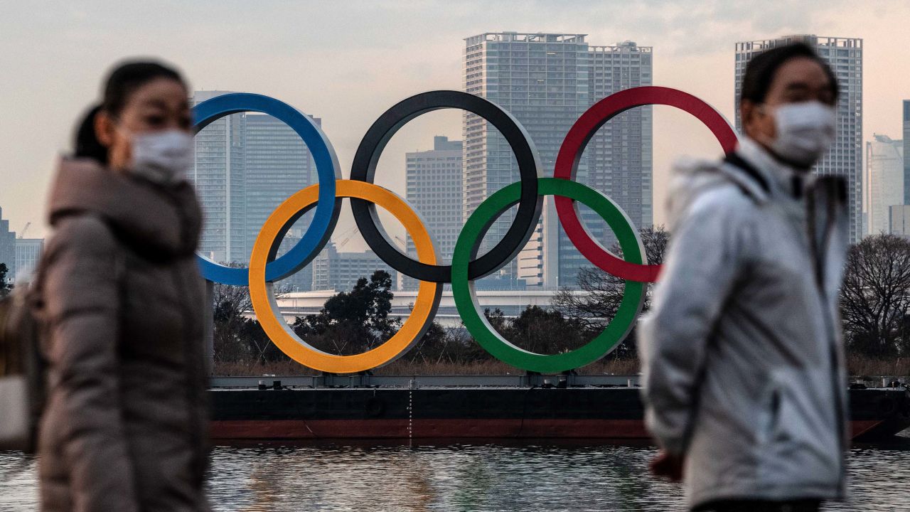 People wearing face masks walk past the Olympic Rings on January 22 in Tokyo.