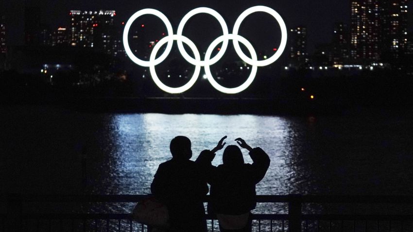 FILE - In this Dec. 1, 2020, file photo, a man and a woman look at the Olympic rings float in the water in the Odaiba section in Tokyo. Opposition to the Tokyo Olympics is growing with calls for a cancellation as virus cases rise in Japan. The International Olympic Committee and local organizers have already said another postponement is impossible, leaving cancellation, or going ahead, as the only options. (AP Photo/Eugene Hoshiko, File)