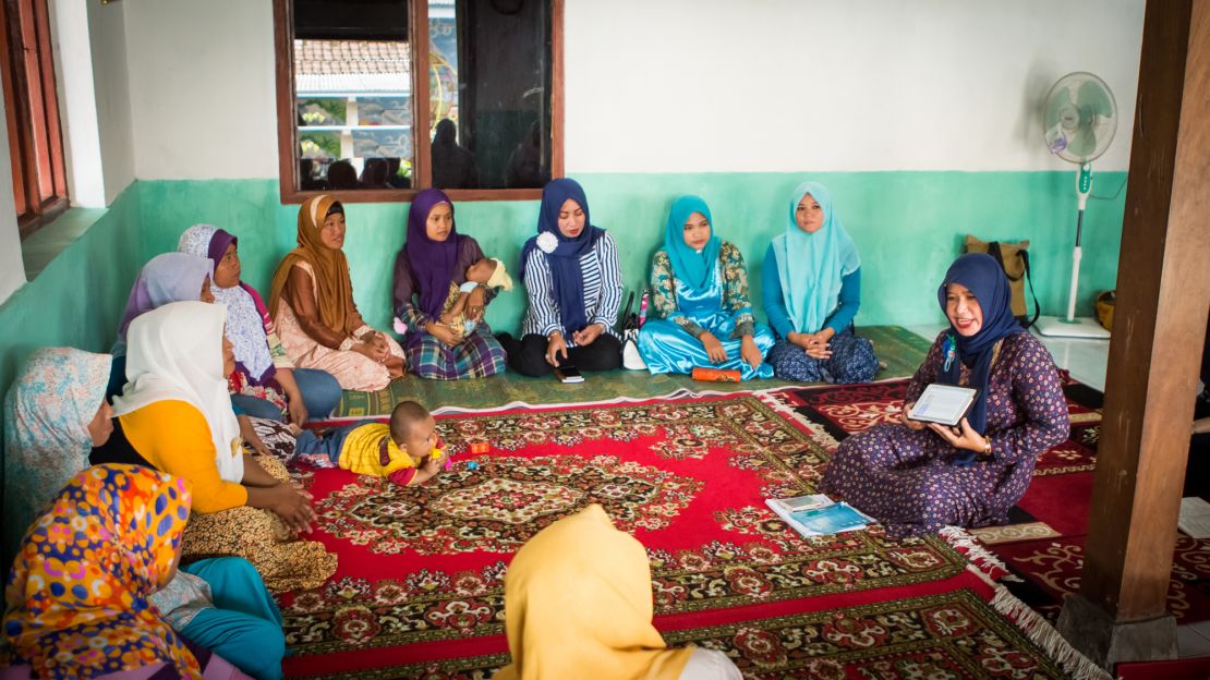Ibu Suparti demonstrates the tablet to other women at a community center in Dompyongan, Klaten, Indonesia, in 2017.