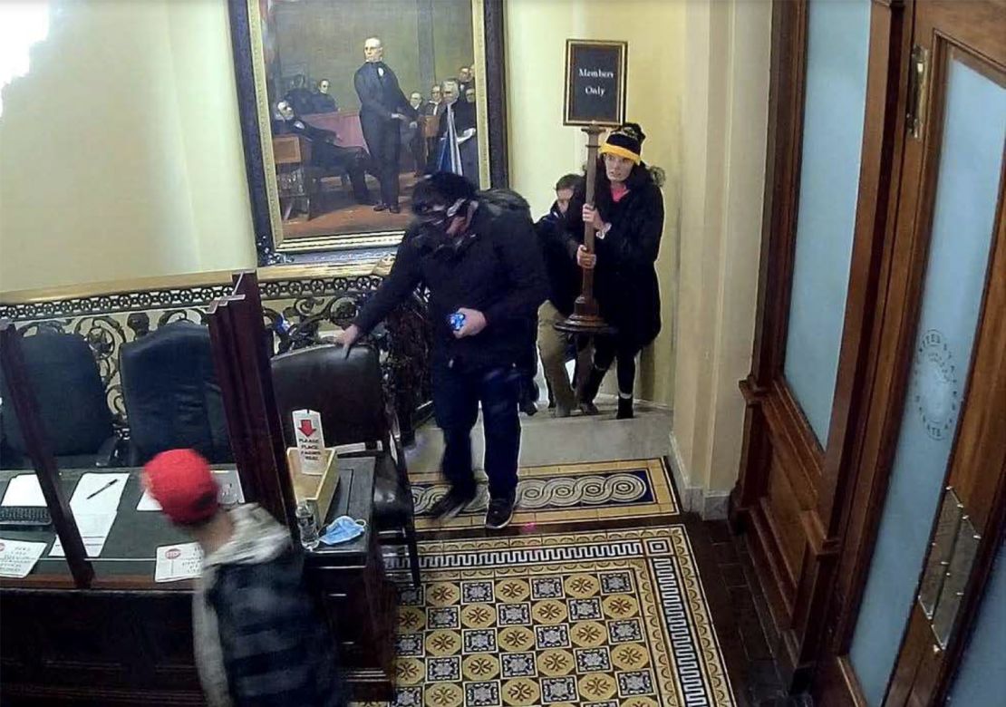 In an image taken from surveillance video, Gracyn Courtright is seen walking up the steps near the Senate Chamber carrying a "Members Only" sign.
