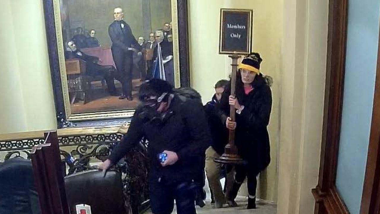 In an image taken from surveillance video, Gracyn Courtright is seen walking up the steps near the Senate Chamber carrying a "Members Only" sign.