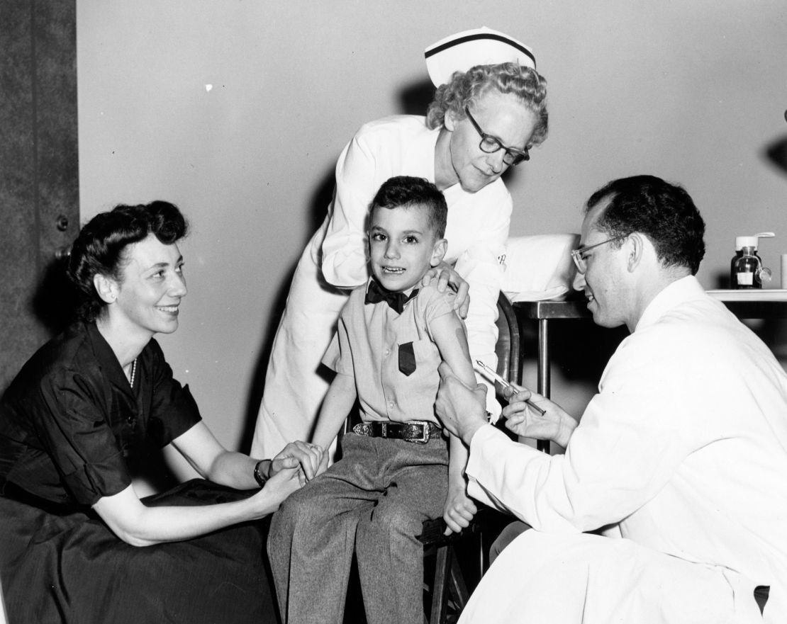 Dr. Jonas Salk gives his son, Darrell, the polio vaccine as his mother looks on in the 1950s.