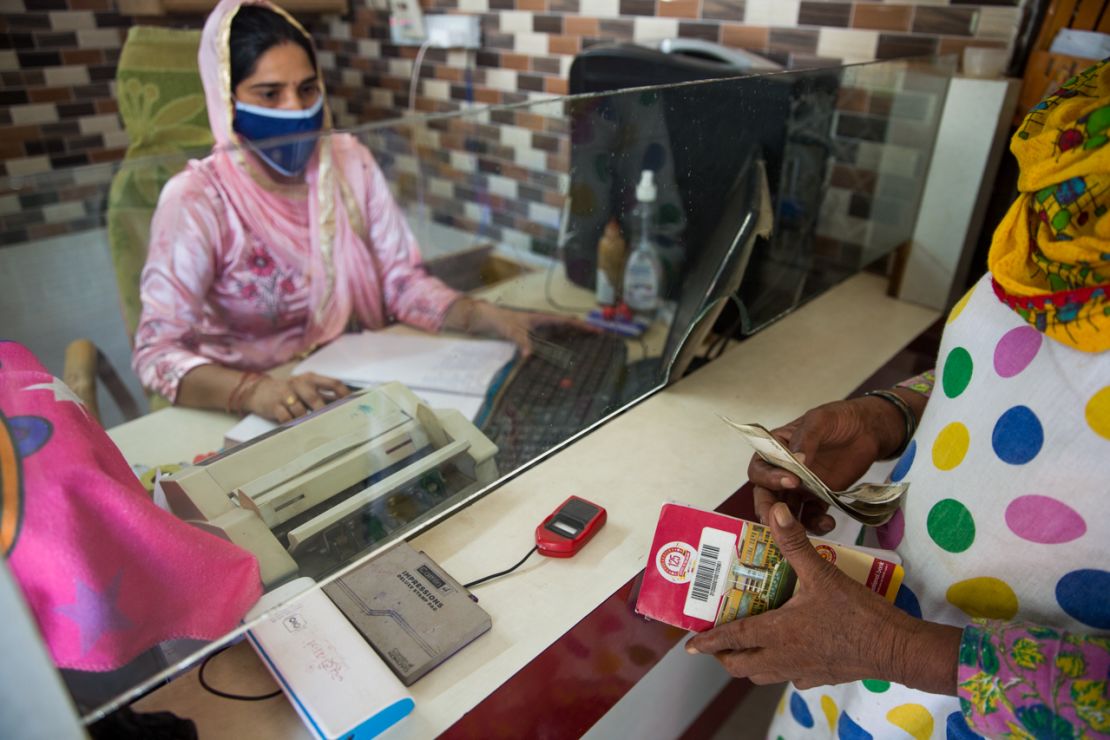 A business correspondent agent helps a woman with a bank transaction in Silana, India.