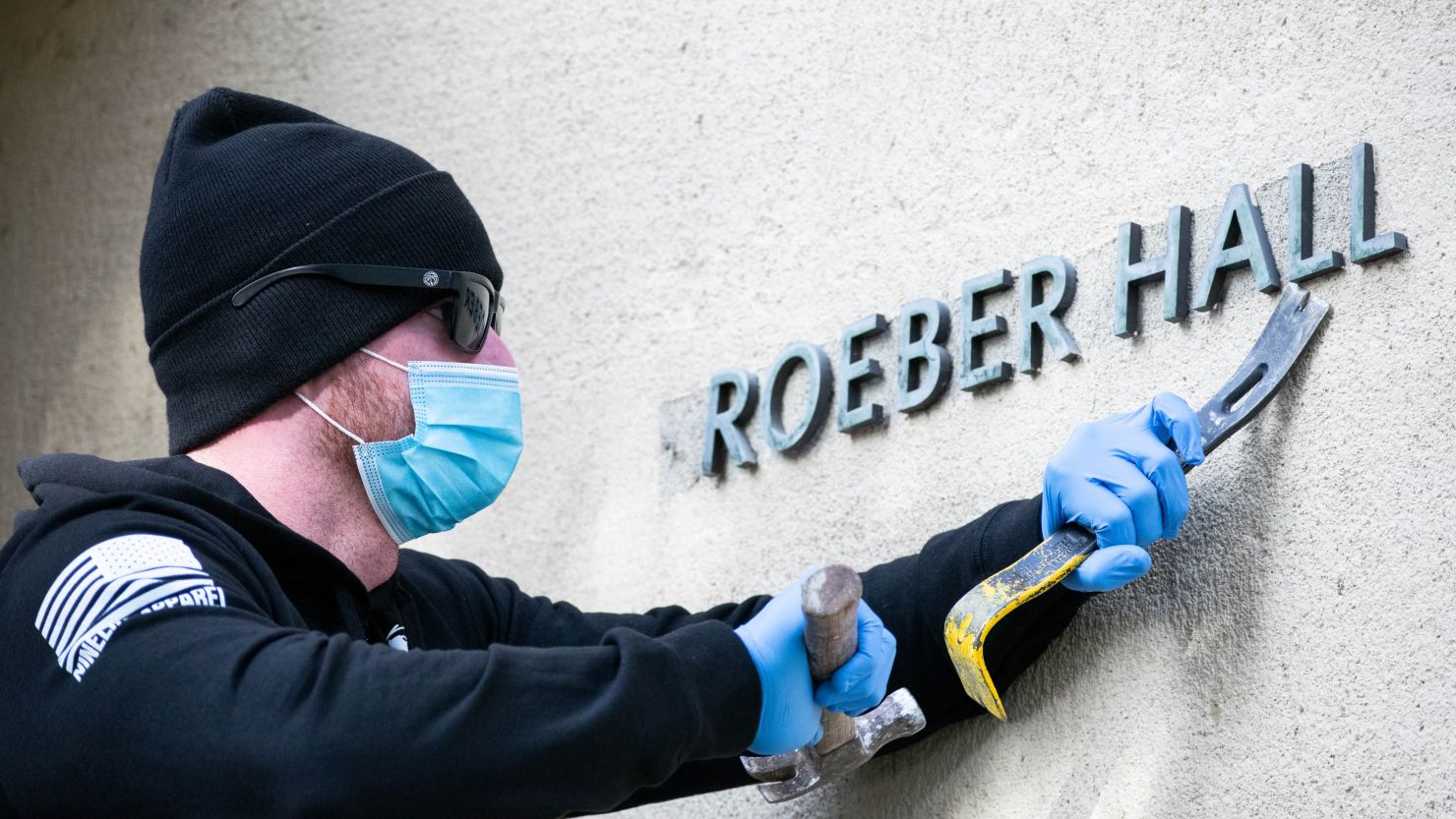 A campus worker removes letters from the exterior of Kroeber Hall on Tuesday, January 26.