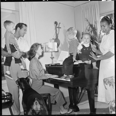 Leachman plays the piano next to her husband and three of their sons in 1957. The children's nurse, Julia Harris, is on the right.