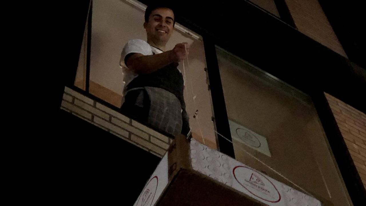 Ben Berman lowers the pizzas to lucky recipients from his second-floor window.