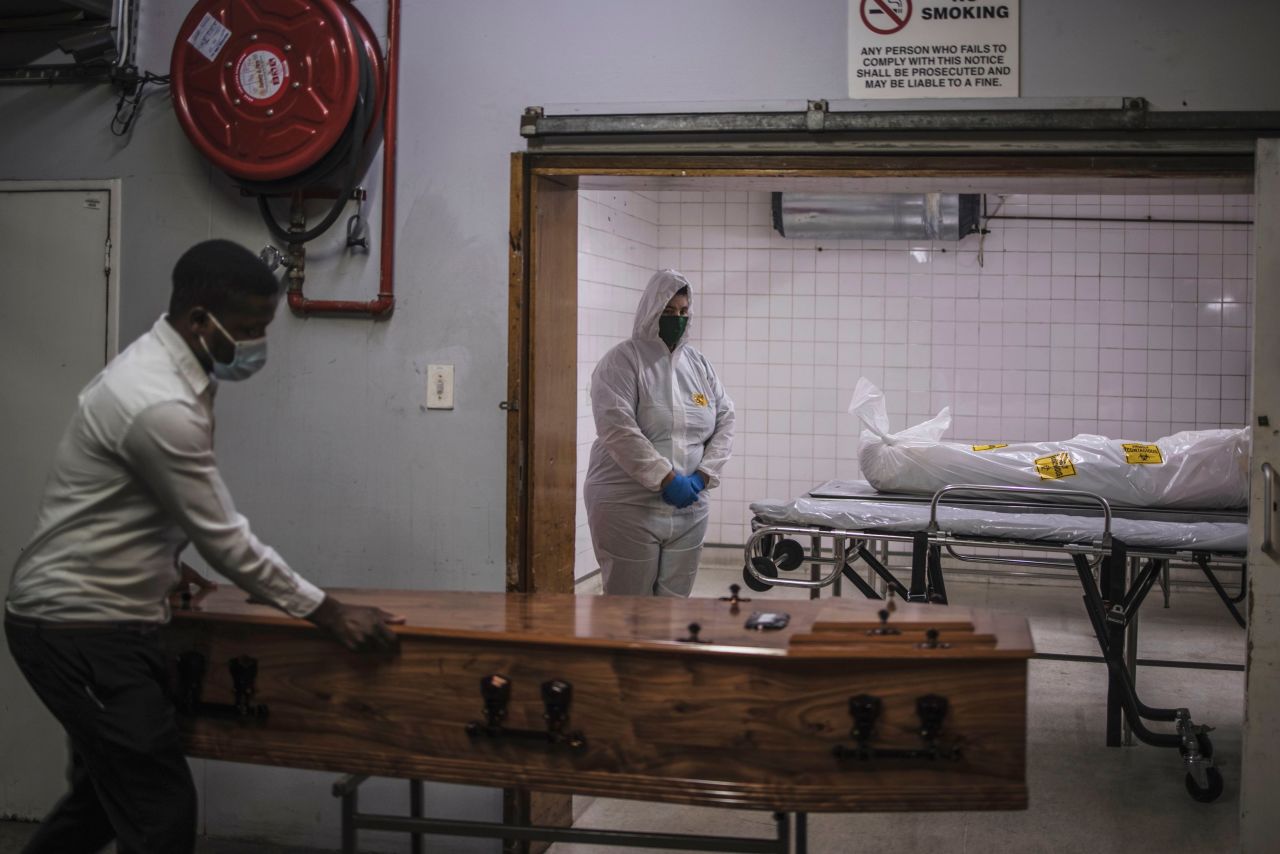 A morgue attendant, right, stands next to the body of a Covid-19 victim in Pretoria, South Africa, on Friday, January 22. Hope stemming from decreasing Covid-19 numbers has been blunted by <a href="https://www.cnn.com/2021/01/28/health/us-coronavirus-thursday/index.html" target="_blank">the spread of new coronavirus variants.</a> One of the most worrisome strains -- <a href="https://www.cnn.com/2021/01/21/health/coronavirus-variant-problem-vaccines/index.html" target="_blank">first found in South Africa</a> -- has been detected for the first time in the United States.