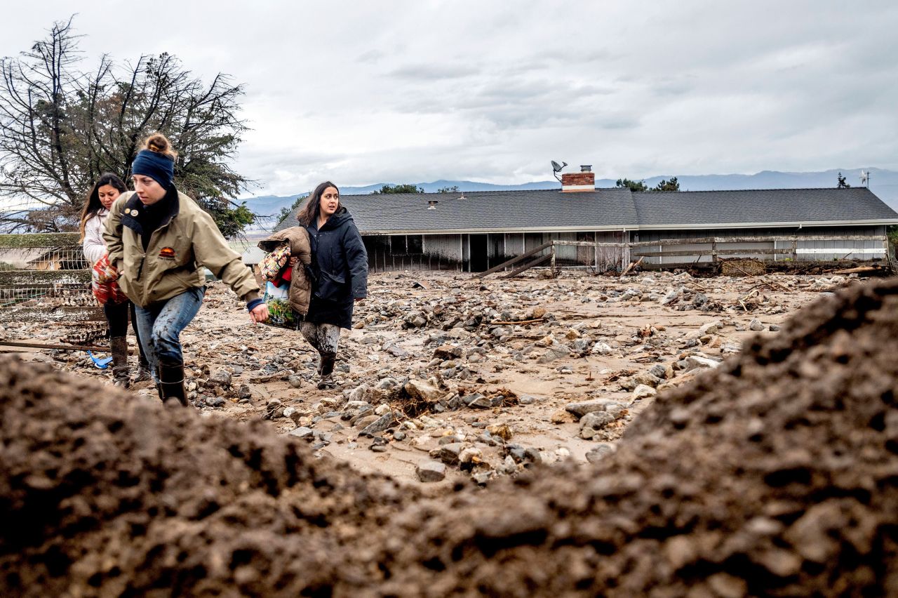 Hana Mohsin, right, carries belongings from a neighbor's home that was damaged in a mudslide in Salinas, California, on Wednesday, January 27. A powerful storm dumped heavy rain and snow on Northern California, <a href="https://www.cnn.com/2021/01/28/us/california-storm-damage/index.html" target="_blank">triggering mudslides and debris flows.</a>