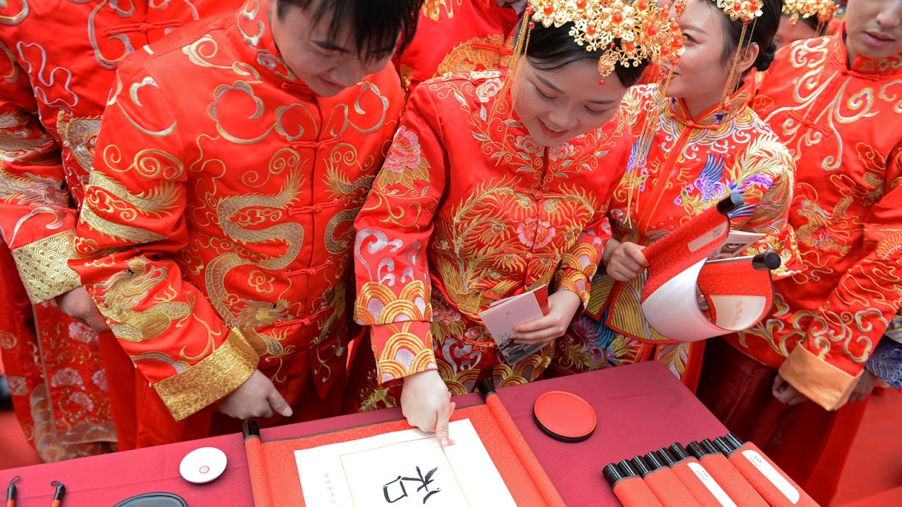 A couple marks fingerprints on ceremonial calligraphy during a traditional group wedding in Changsha, China.