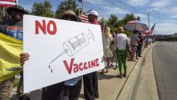 WOODLAND HILLS, CA - MAY 16: A protester holds an anti-vaccination sign as supporters of President Donald Trump rally to reopen California as the coronavirus pandemic continues to worsen, on May 16, 2020 in Woodland Hills, California. The protesters, organized by the activist group, Latinos 4 Trump 2020, are angry about restrictions related to the virus that causes COVID-19 disease and are calling for such restrictions regarding businesses, social distancing and recreational movement to end as soon as possible.  (Photo by David McNew/Getty Images)