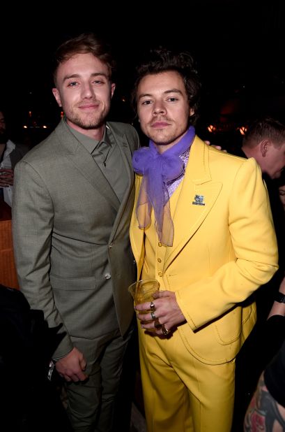 British Radio DJ Roman Kemp and Harry Styles at the 2020 Brit Awards. Styles wears a canary yellow Marc Jacobs suit with purple tulle tie.