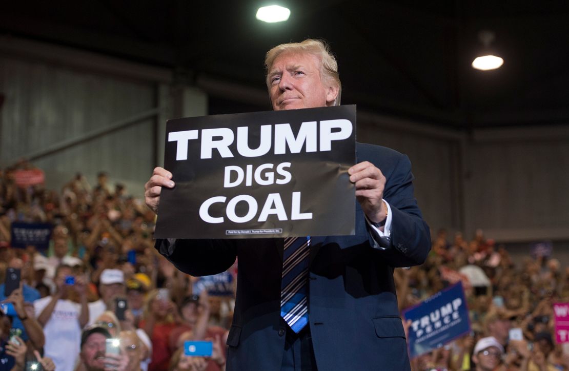 President Donald Trump holds up a "Trump Digs Coal" sign as he arrives to speak during a Make America Great Again Rally at Big Sandy Superstore Arena in Huntington, West Virginia, August 3, 2017.