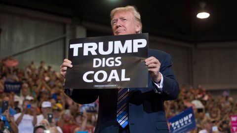 President Donald Trump holds up a "Trump Digs Coal" sign as he arrives to speak during a Make America Great Again Rally at Big Sandy Superstore Arena in Huntington, West Virginia, August 3, 2017.