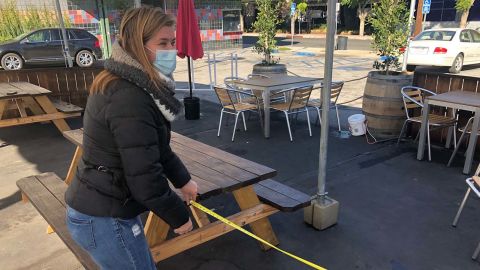 Angela Marsden of the Pineapple Hill Saloon and Grill in Sherman Oaks, California, measures the distance between tables at her outdoor dining area.
