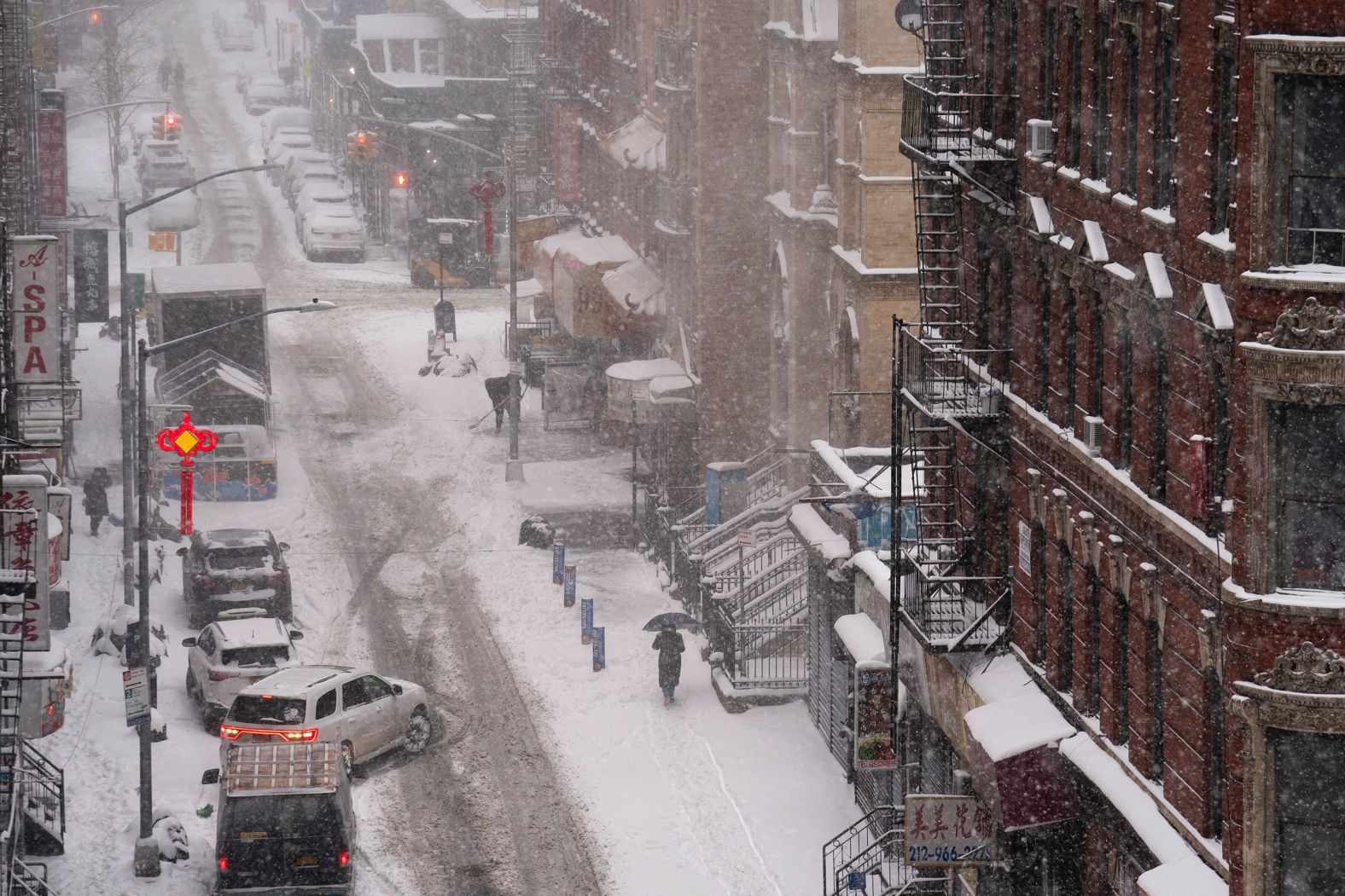A pedestrian walks down a snow-covered sidewalk in the Chinatown neighborhood of New York on Monday.