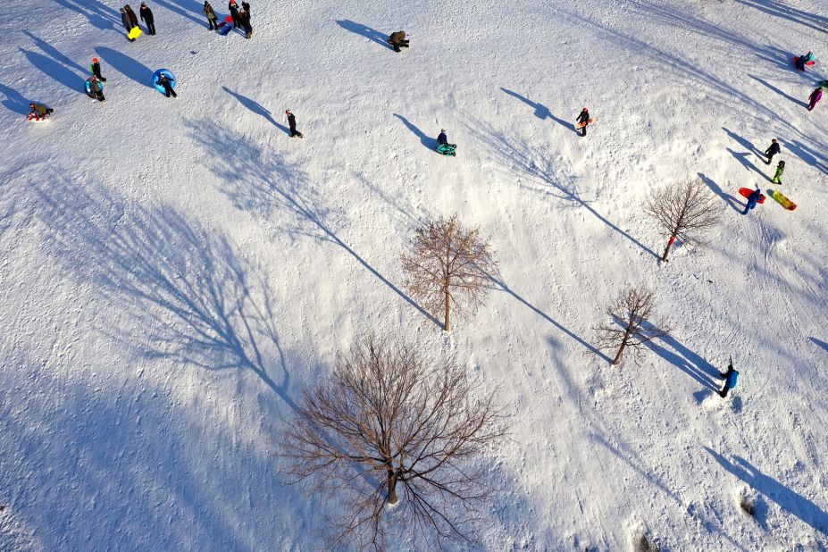 Sledders walk up a hill in Chicago's Humboldt Park on Monday.