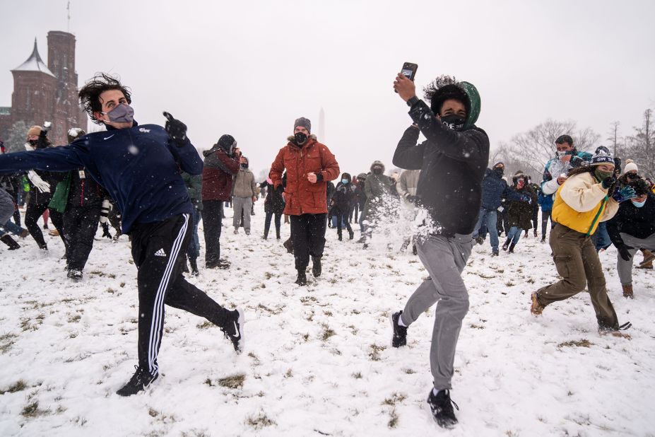 People take part in a snowball fight as snow blankets the National Mall in Washington, DC.