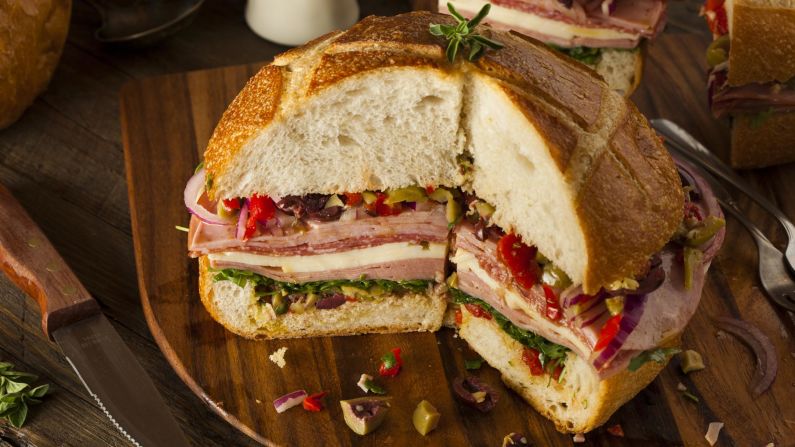 <strong>New Orleans: </strong>A muffuletta features three kinds of meat and two types of cheese, along with pickled peppers and olive spread on a round loaf of bread.