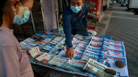 A newspaper seller points at a front-page of a newspaper in Yangon, Myanmar, Febuary 2, 2021. 