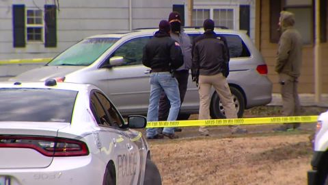 Investigators stand Tuesday outside an Oklahoma home where police say five children and a man were shot dead.